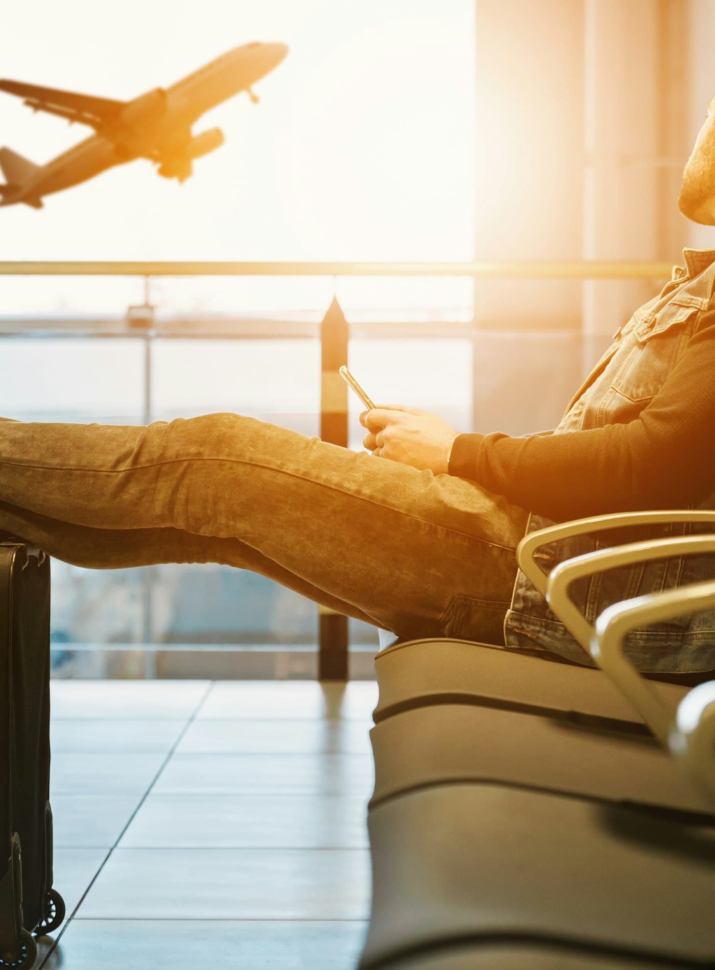 A traveller waiting in an airport departure lounge as an aircraft takes off
